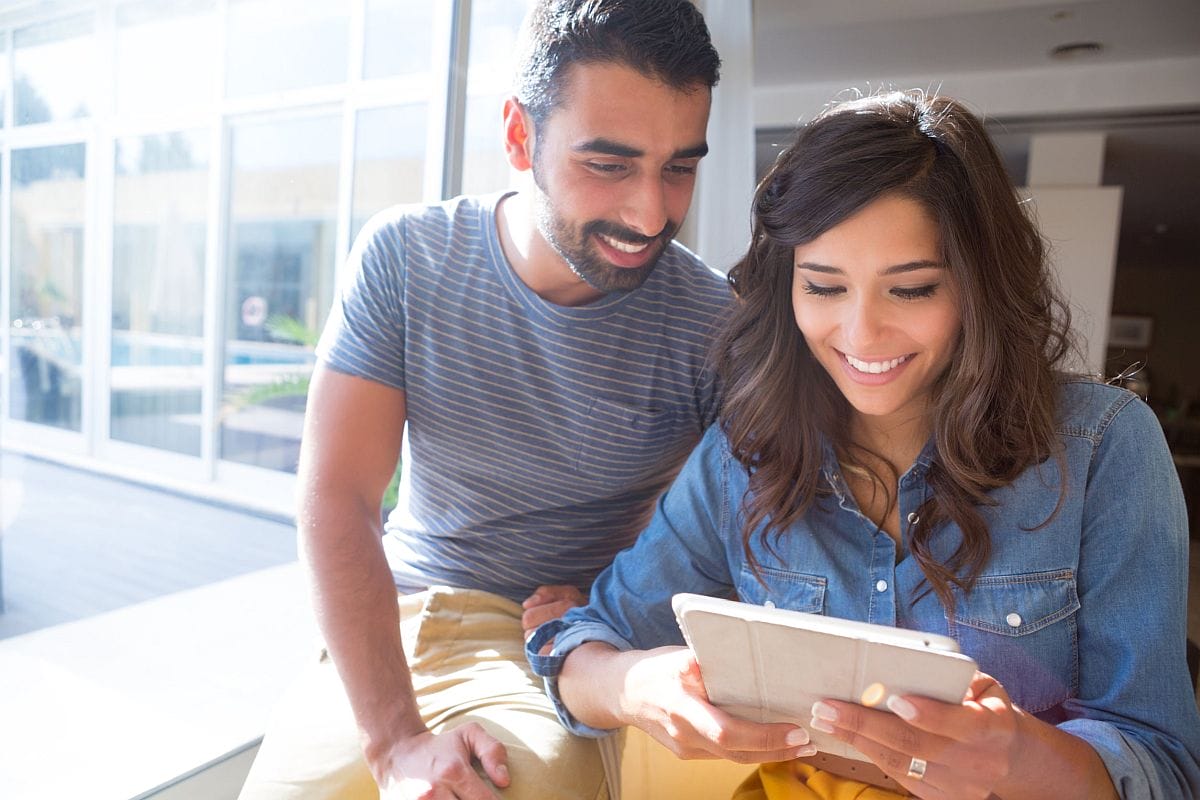 smiling woman and man look at a smartphone; patient hub enrollment concept