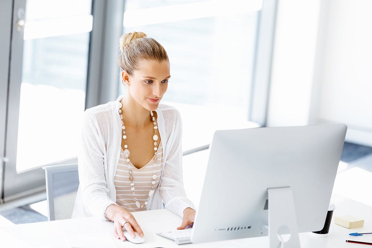 doctor in white dress and labcoat types on a desktop computer; patient hub enrollment concept