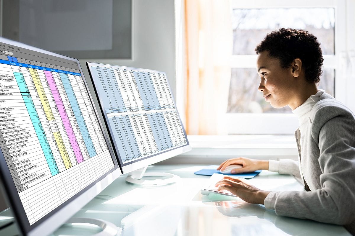 Person at desktop looking at data on two monitors; data insights concept