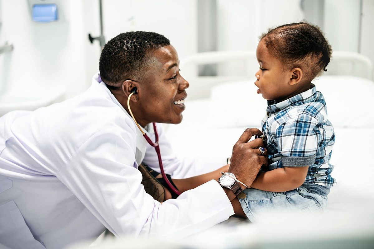 Smiling doctor using stethoscope to check toddler; key opinion leaders concept