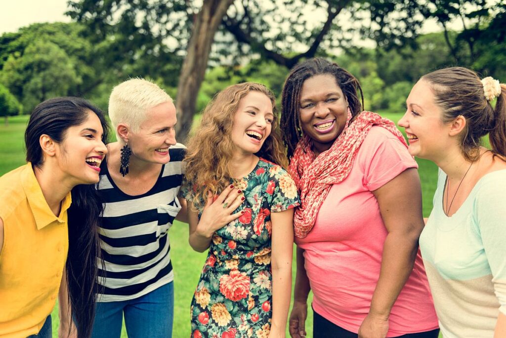 Group of women standing close together and laughing; rare disease communities concept
