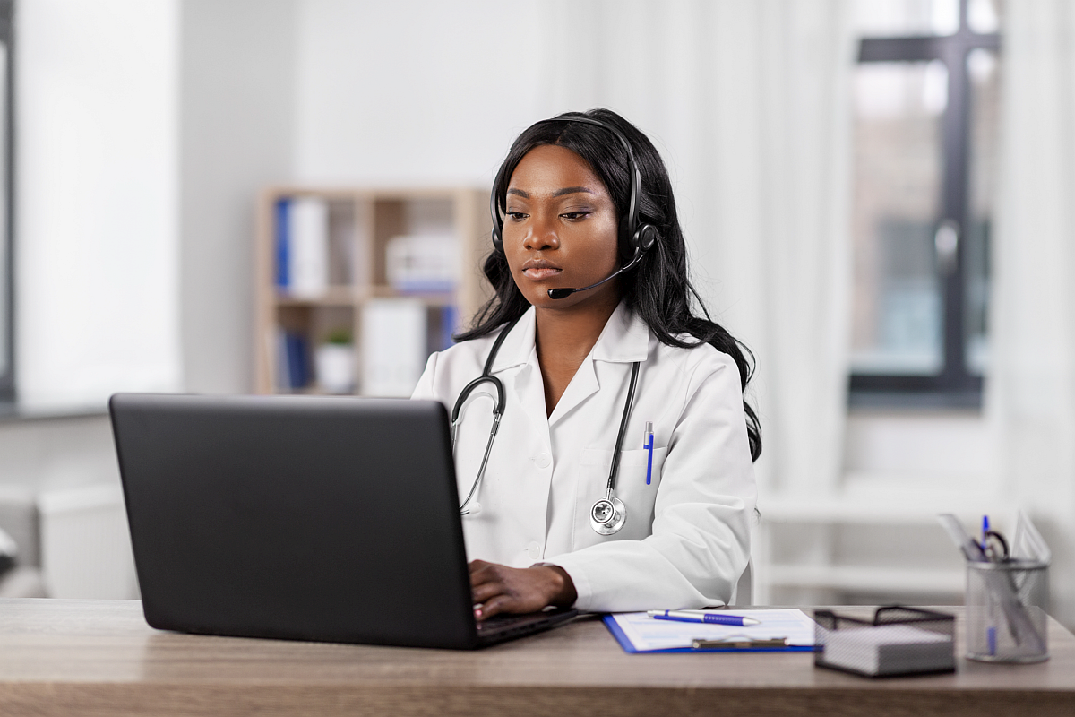 doctor using laptop wearing headset; prior authorization concept