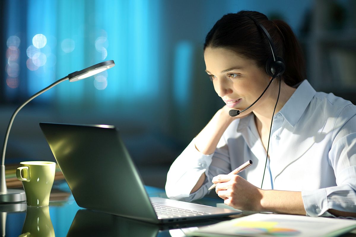 Professional woman working online with laptop and headset; better economic models concept