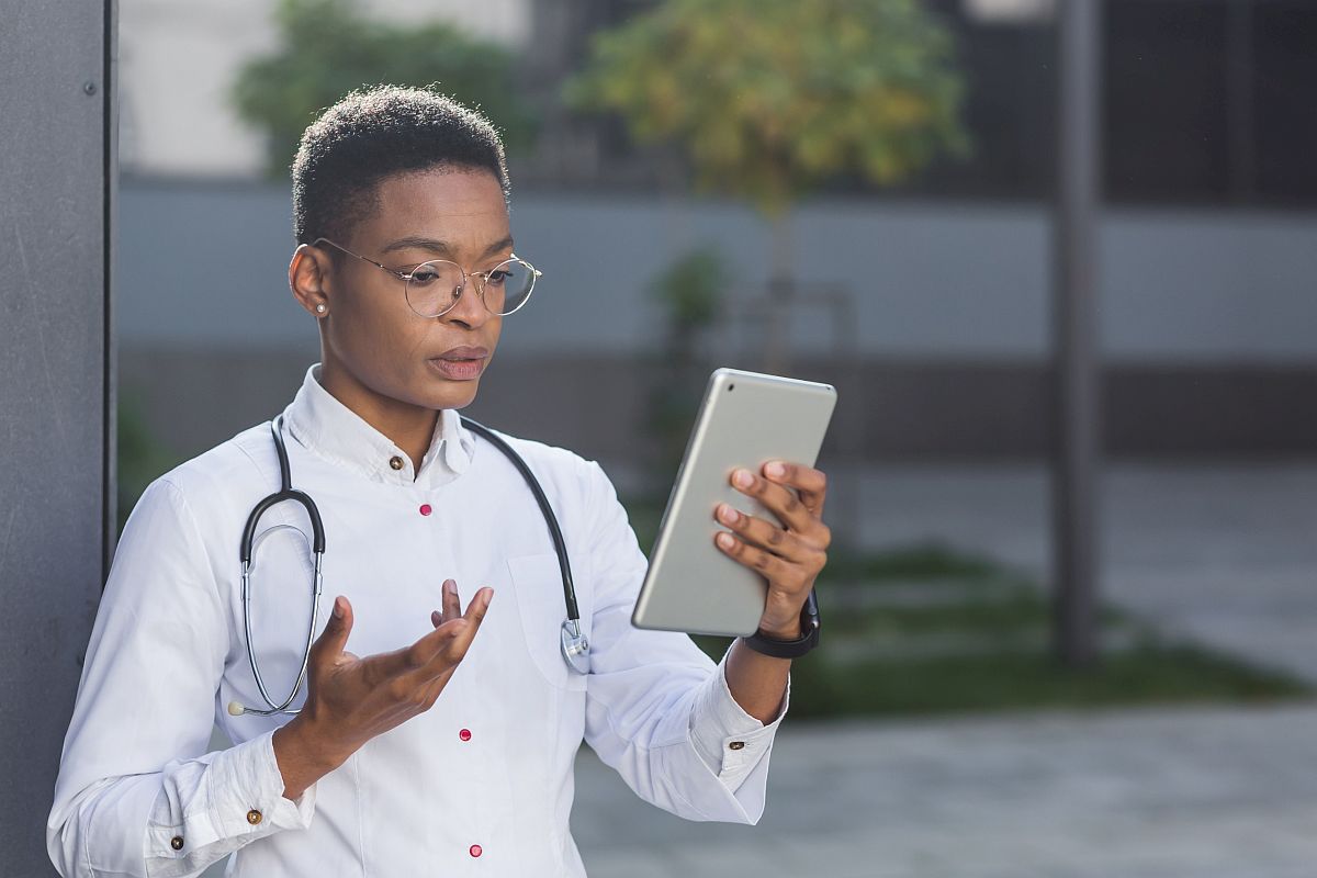 Female doctor holds online conversation on a tablet; specialty drug access concept