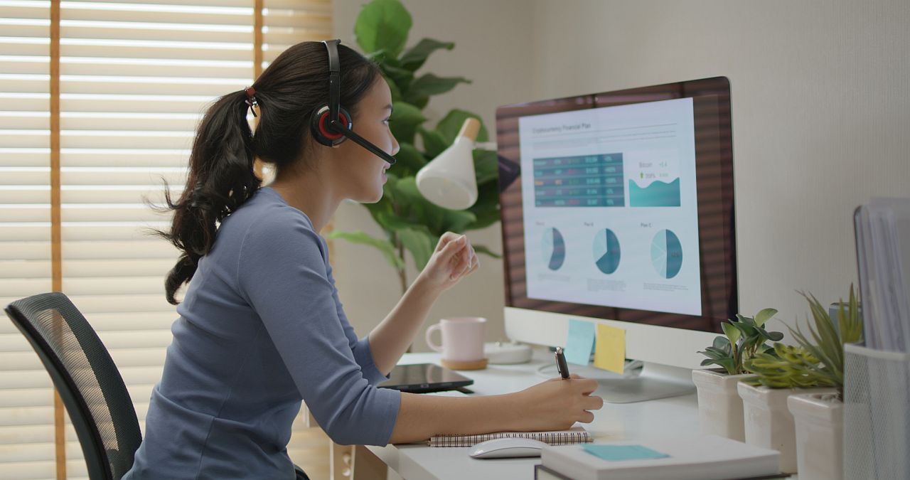 Young woman at computer with headset; specialty therapies concept.