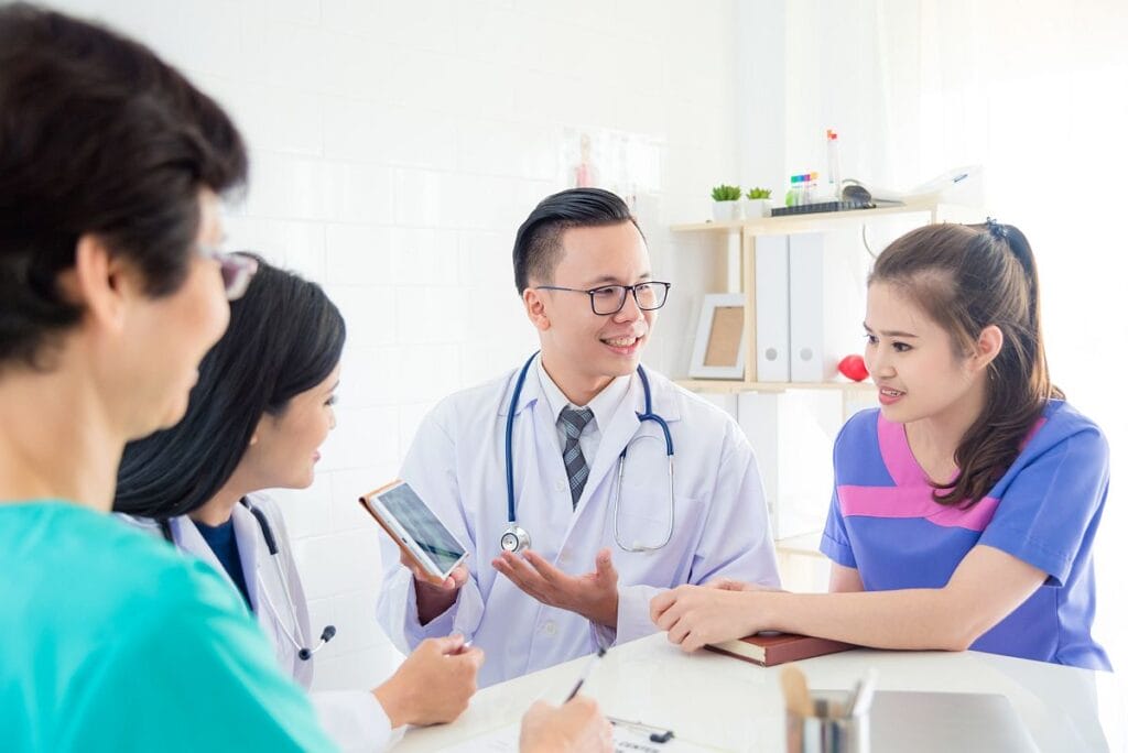 Healthcare professionals sitting around a table, having a discussion; nonadherence concept