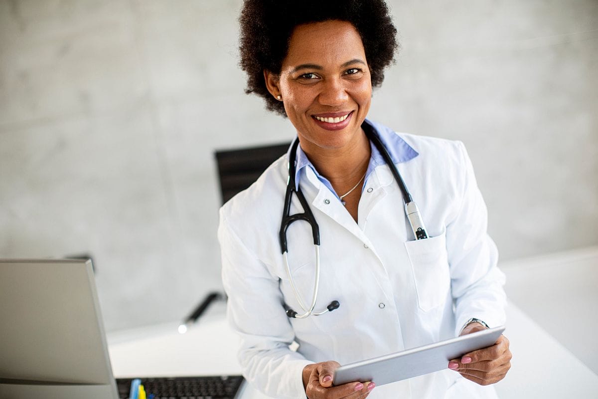 Smiling doctor holding tablet; patient nonadherence concept