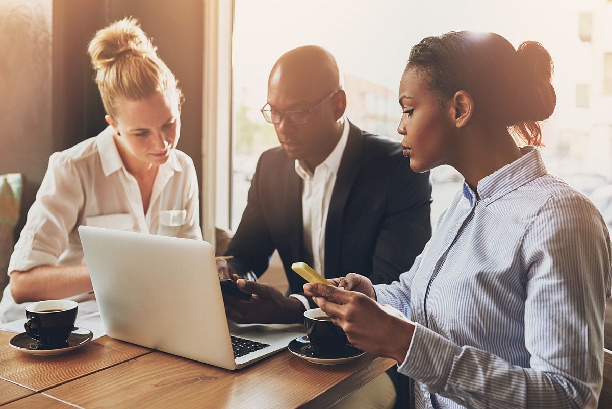 Group of professionals gathered around a laptop, phones in hand; automated contract tracking concept