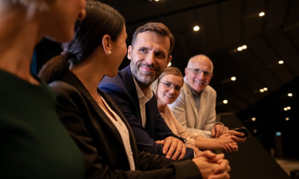 Group of business people, seated in auditorium, talking; successful product launch concept