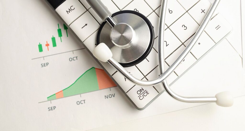 Close up of stethoscope lying on top of calculator and graph print-out; specialty drug market concept