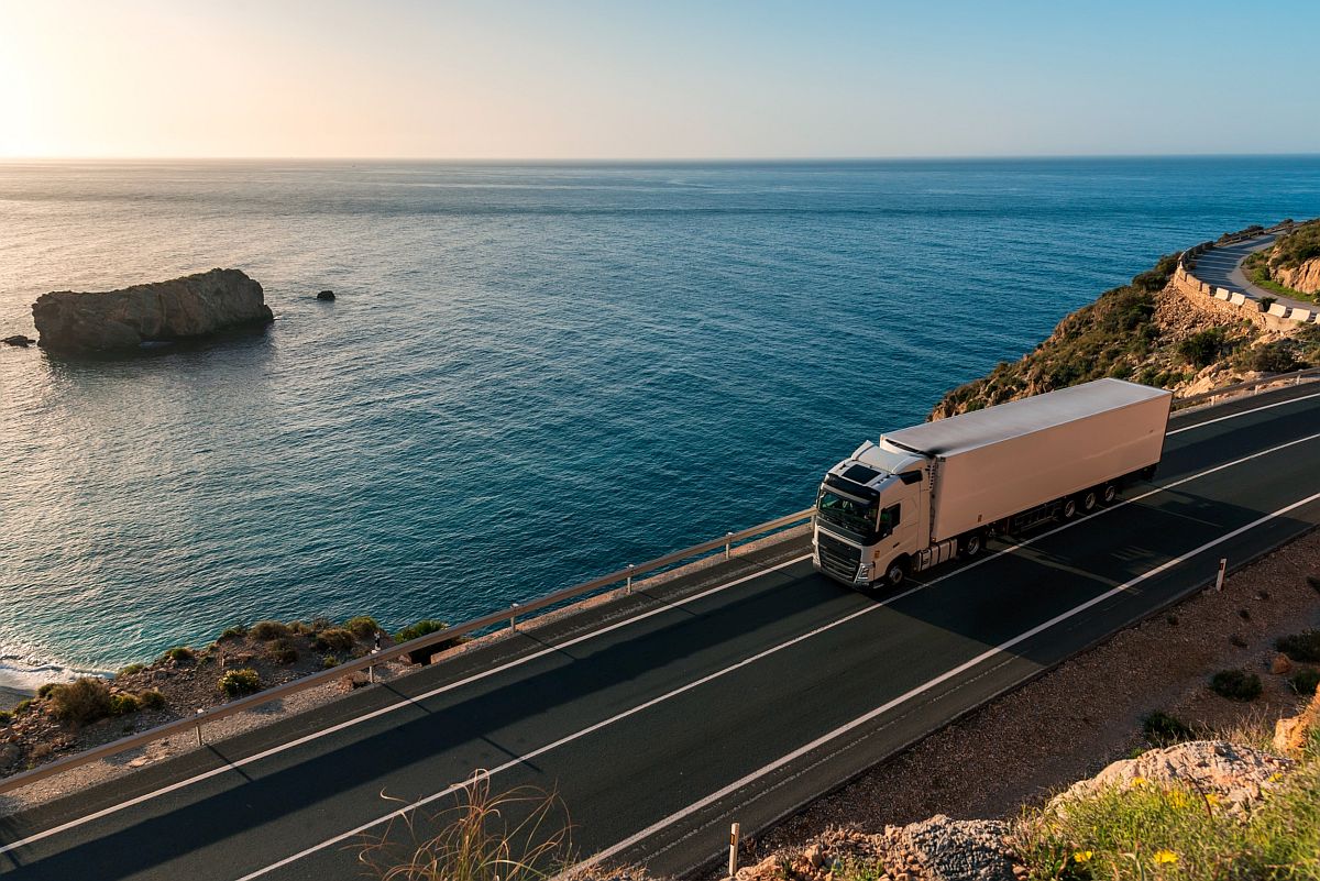 Tractor trailer driving along a highway next to the ocean; pharmaceutical supply chain concept