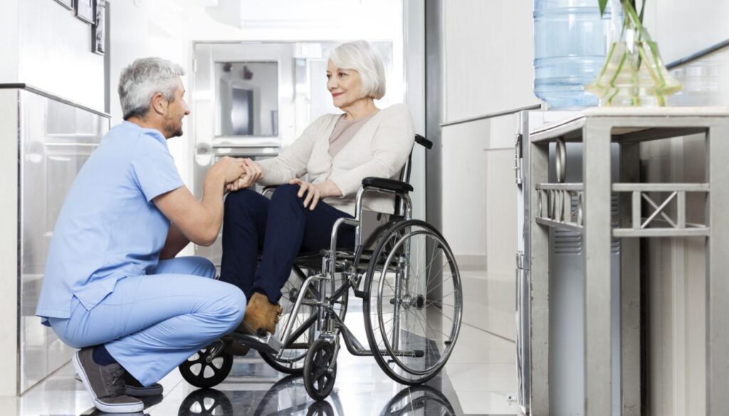 women in wheelchair chats with nurse; drug pricing concept