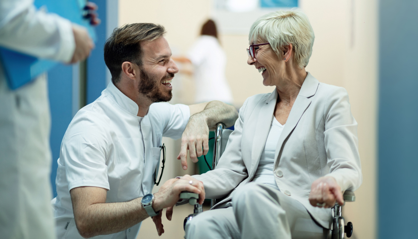 Healthcare professional laughing with woman in a wheelchair; collaborative patient management concept