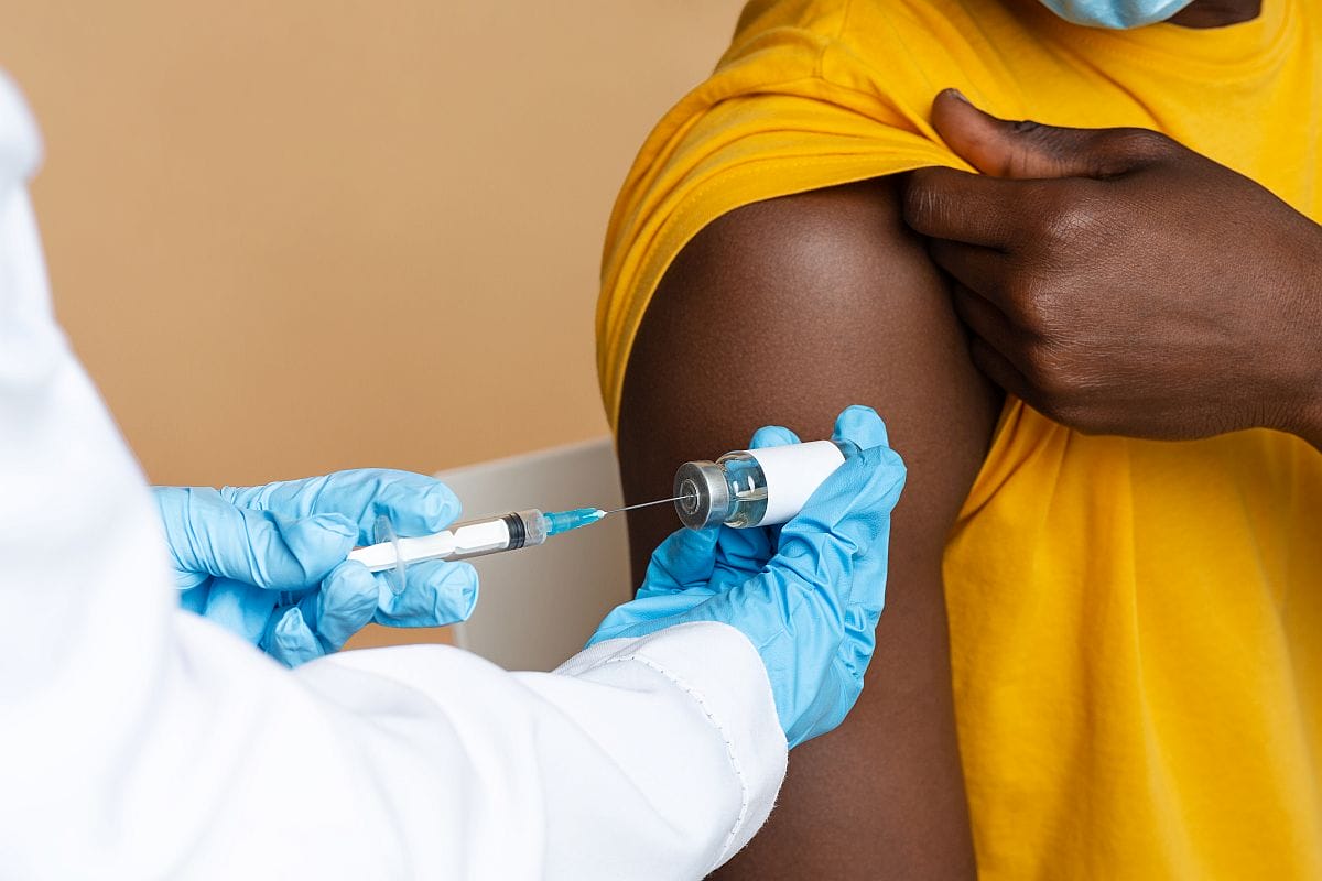 Doctor in blue medical gloves taking dose of vaccine; financial assistance rare disease concept