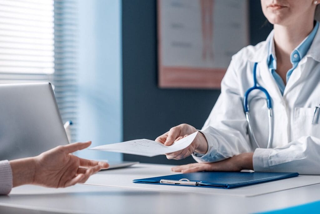 Doctor seated at desk giving a document to a patient; paid fill rate concept