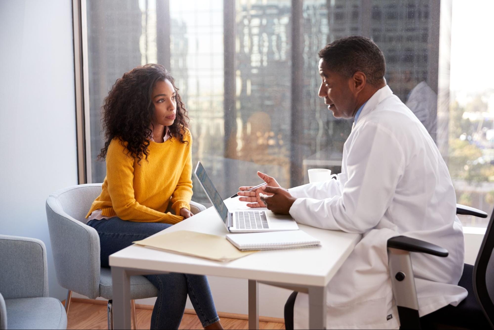 Healthcare professional in white coat sitting at desk across from woman; new uses for orphan drugs concept