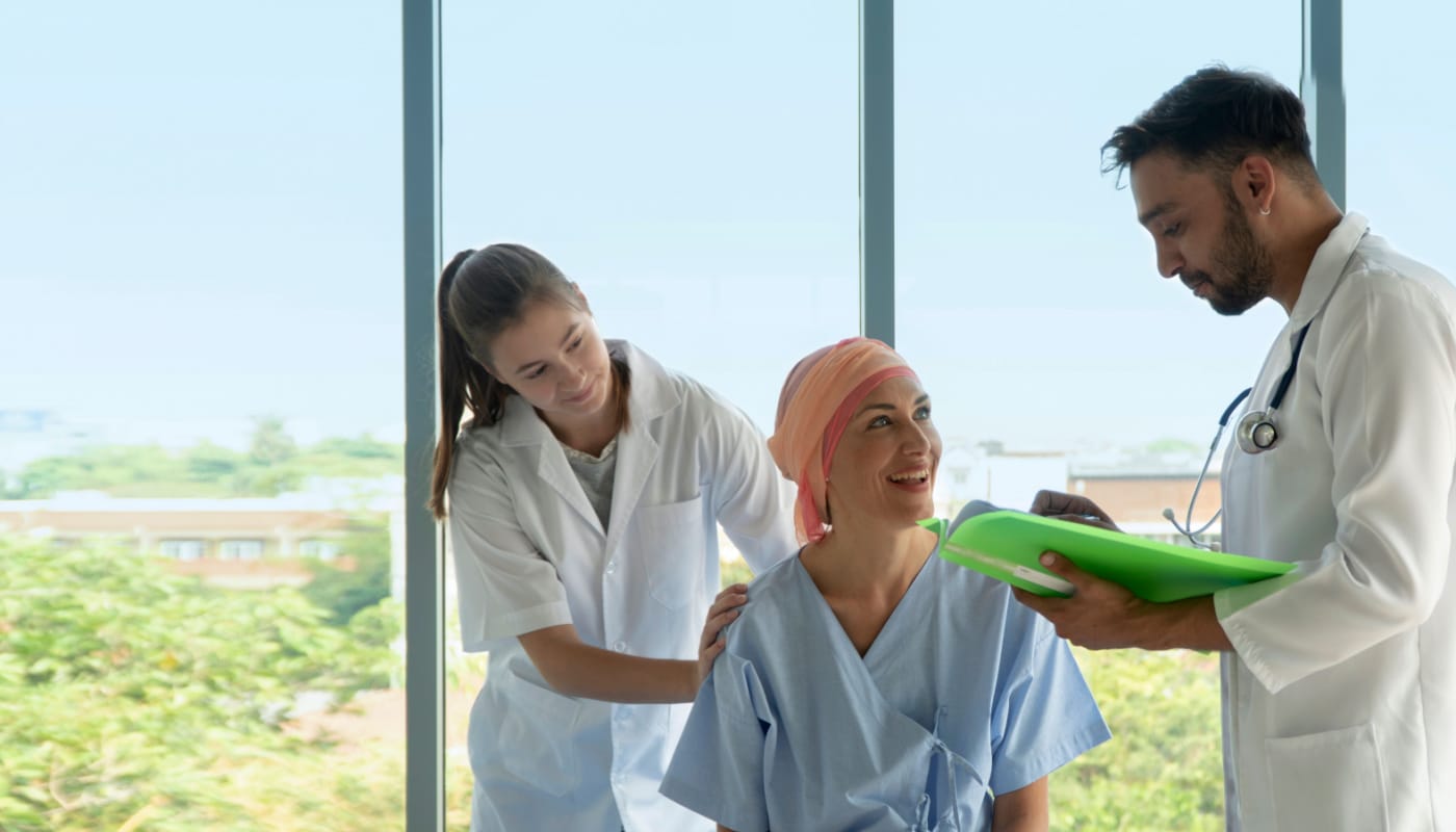 Two healthcare professionals with smiling patient; Patient Services concept