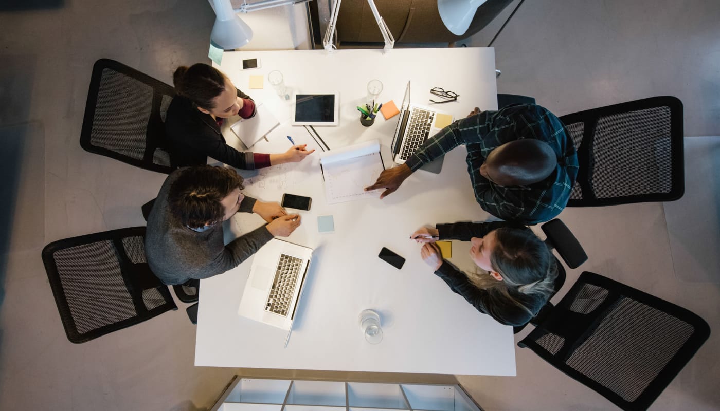 Overhead view of team sitting at a table, analyzing data; pharma brand benchmarking concept